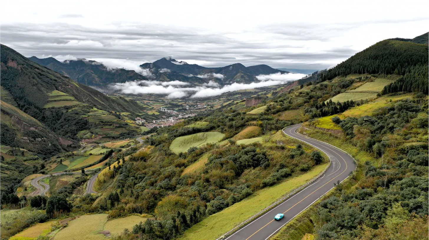 Carretera de montaña entre lomas verdes de los Andes, con niebla en los valles y un carro eléctrico teal a lo lejos